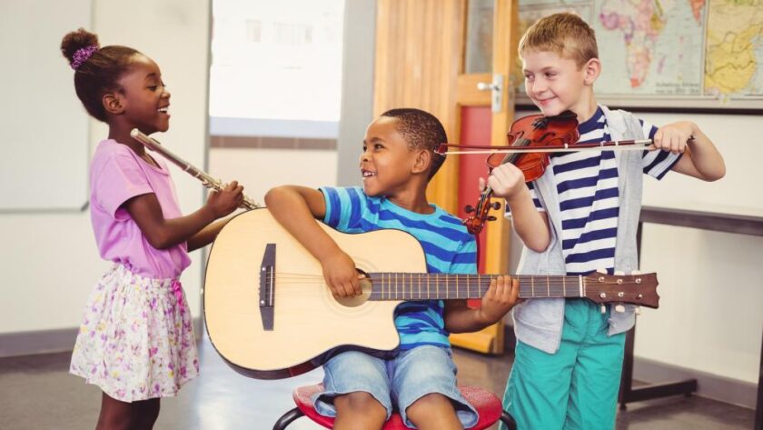 smiling-kids-playing-guitar-violin-flute-in-classroom